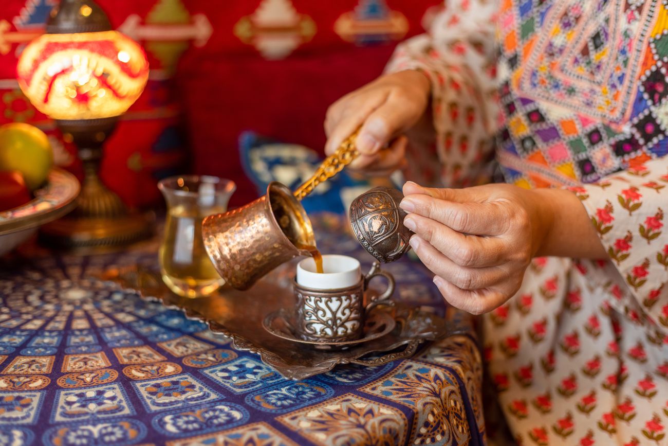 Turkish coffee poured from a copper cezve into a small cup