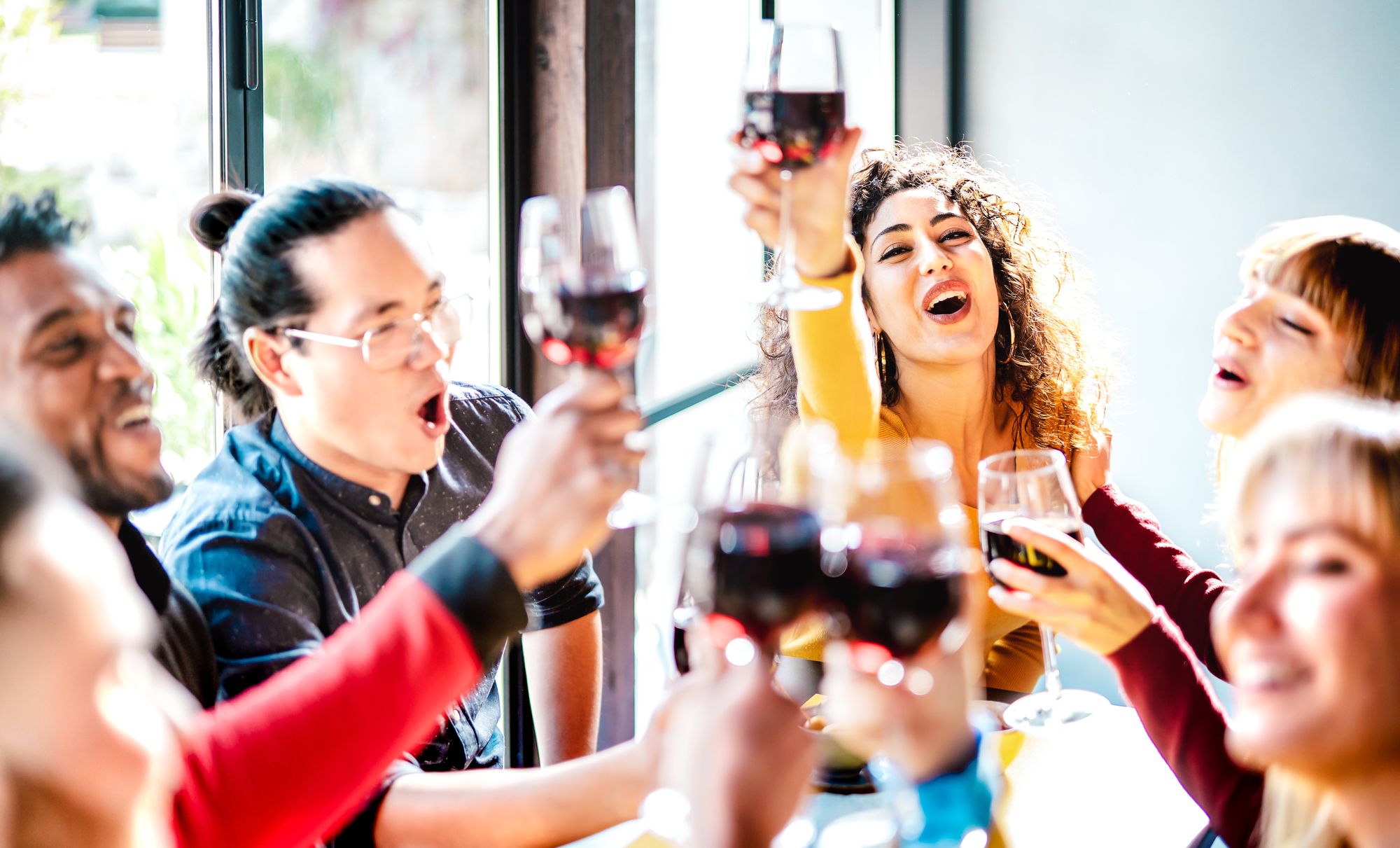 Friends raising a toast around a warm, candlelit dinner table