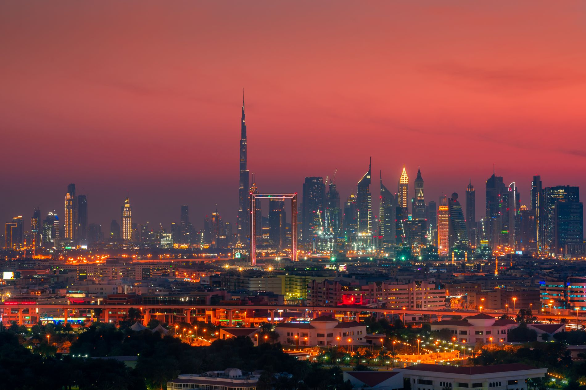 The Dubai skyline lit up at night, reflected in the water