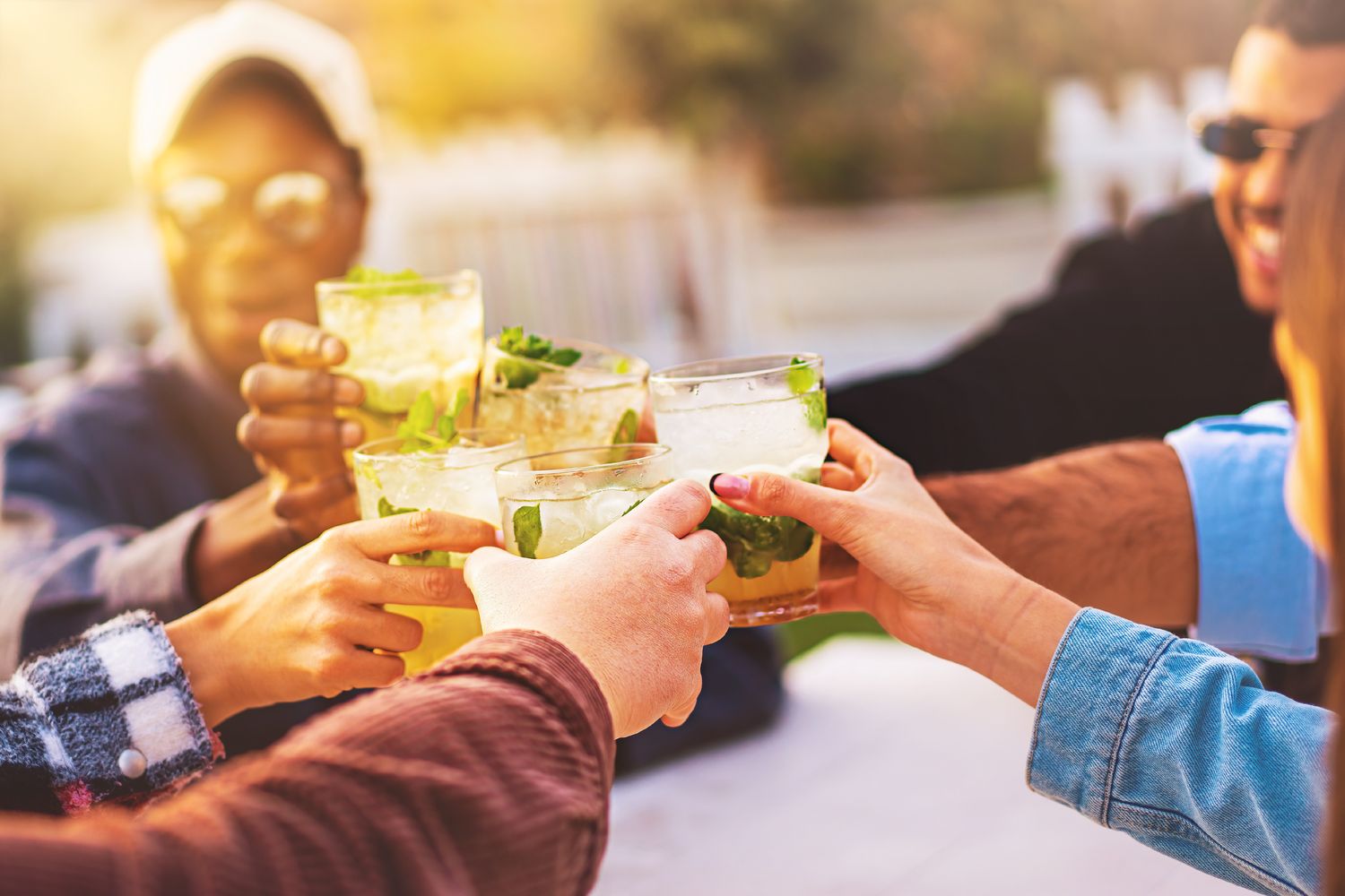 Friends clinking cocktail glasses at a softly lit lounge bar